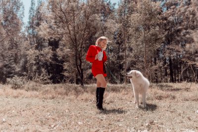 Woman in red dress grinning at a white dog