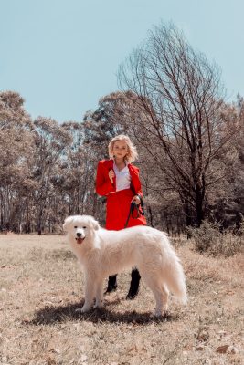 Woman in red dress posing behind white dog