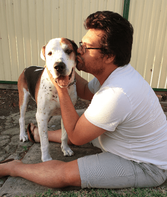 Man in glasses kissing dogs face