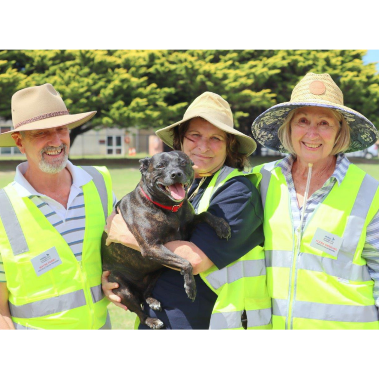 A man and two women, one of whom is holding a black dog