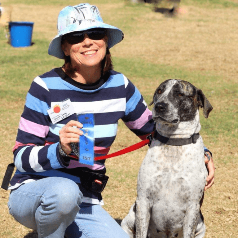 A woman with her dog, showing off its first place certificate